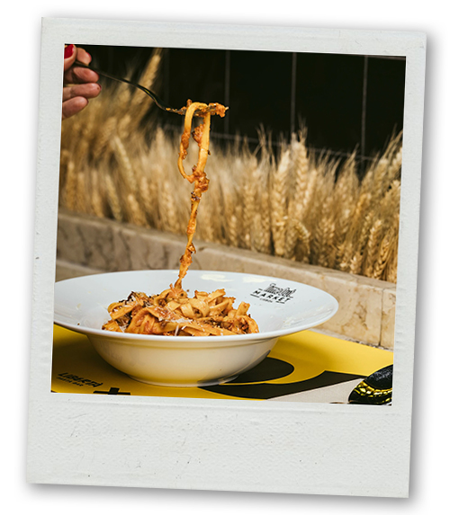 A Polaroid of someone enjoying some pasta from a bowl that is branded with Timeout market