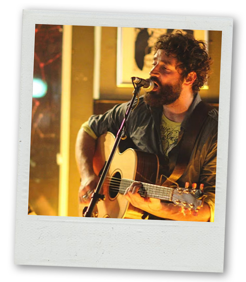A Polaroid of a male musician playing guitar and singing