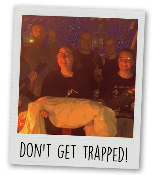 A Polaroid of Last Night of Freedom staff posing in a zombie themed escape room with the caption Don't Get Trapped