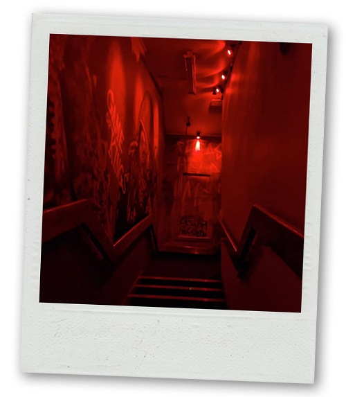 A Polaroid of a creepy looking staircase leading up to horror-themed escape rooms