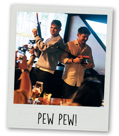 A Polaroid of two men holding replica VR guns with the caption Pew Pew