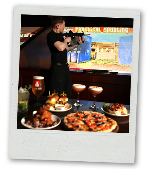 A Polaroid of a man shooting a VR gun with a table with food and drinks in the foreground