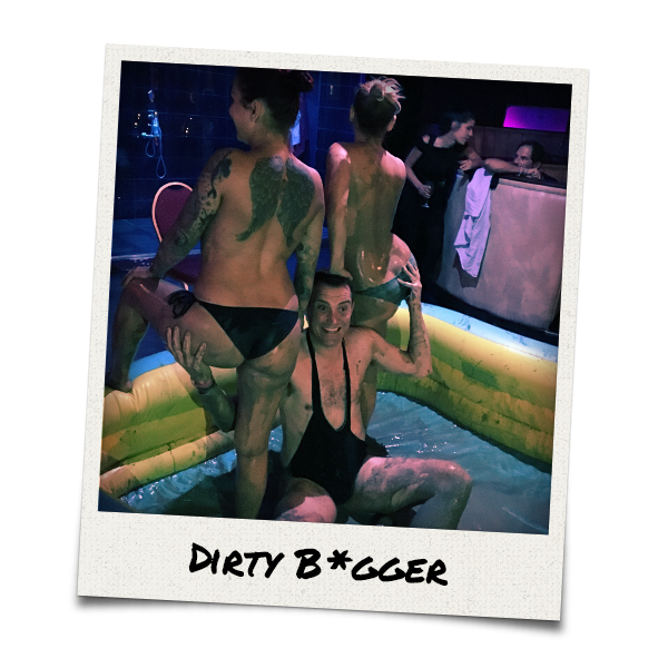 Two strippers with a man in a mud wrestling ring