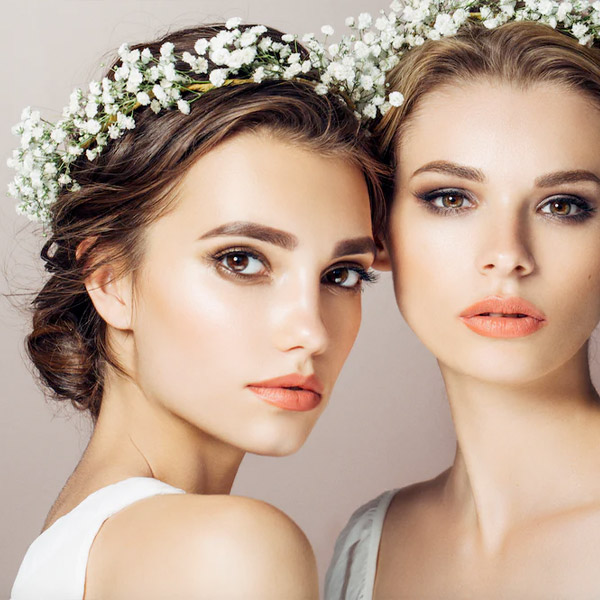 Two brides with flower crowns looking into the camera