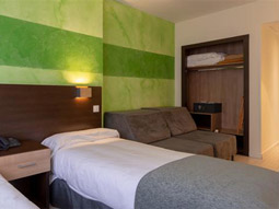 A single bed in a room decorated with green striped wallpaper and a pull out sofa bed beside it at Apartamentos Serrano Recoletos in Madrid
