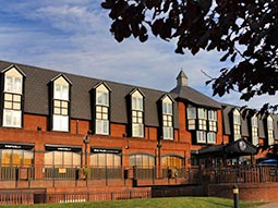 A large double room with striped carpet and TV on the desk in front of the bed