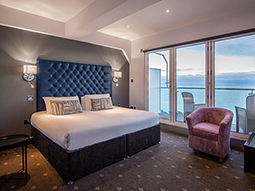 A room with a king bed and balcony that overlooks the sea at Suncliff Hotel