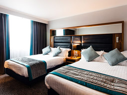 Two double beds with a bedside table between them at Crowne Plaza Leeds