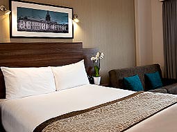 A double bed with a panramic photograph hung above it