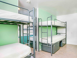 A green themed room with sets of bunkbeds and storage underneath them at Hans Brinker Hotel 