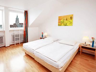 Two white single beds in a hotel room with bedside tables on either side