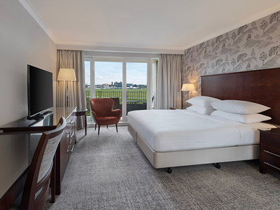 A double bed in a room with a balcony and a large TV in front of it at Delta Hotels by Marriott York