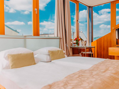 A double bed in a room with windows showing a view of the city at Wenceslas Square Hotel