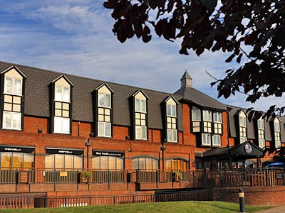 A large double room with striped carpet and TV on the desk in front of the bed