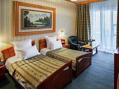 A traditional twin room with a net curtain at the window and a blue carpet
