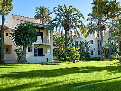 The green garden and white exterior of the Blue Bay Banus Hotel, during the day