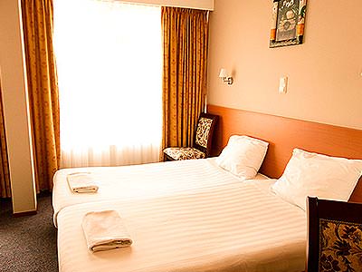 Two single beds with white bedding, in a room with a window in the background