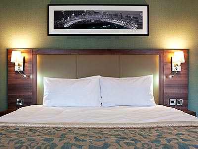 A double bed with a photograph hung above it