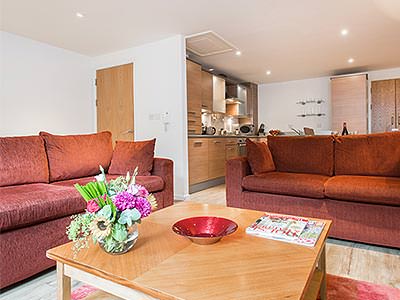 Two red sofas around a coffee table, with a kitchenette in the background
