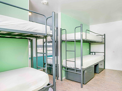 A green themed room with sets of bunkbeds and storage underneath them at Hans Brinker Hotel 