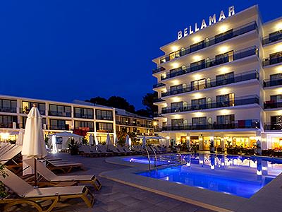 Sun loungers around an outdoor pool, outside the Bellamar Hotel at night