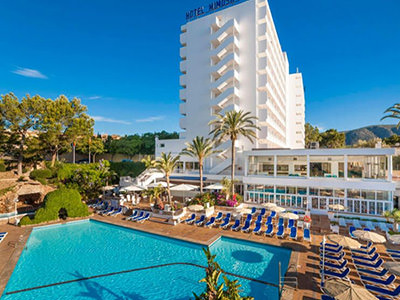 Two beds topped with red bedding, with French doors leading onto a balcony in the background