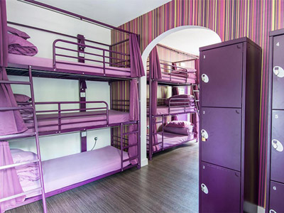 Bunkbeds in a room with striped walls and purple lockers at Safestay London Holland Park