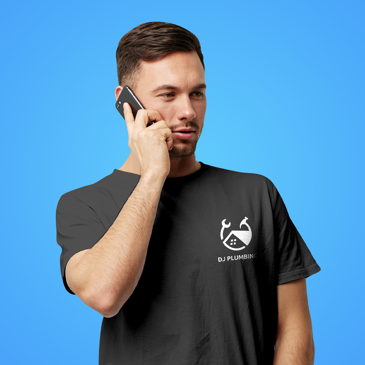 Man on the phone wearing black T-shirt with a white logo that reads DJ Plumbing