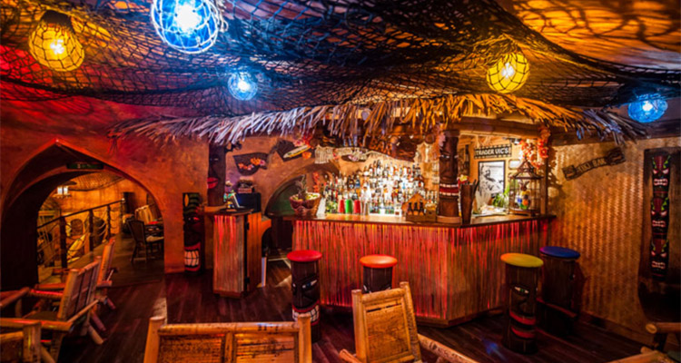 Rumpus Tiki Bar which is a brightly coloured tikki bar with a wooden bar and colourful bar stools with faces