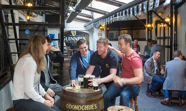 A group of people sat in the beer garden at O'Donoghue's, with others in the background