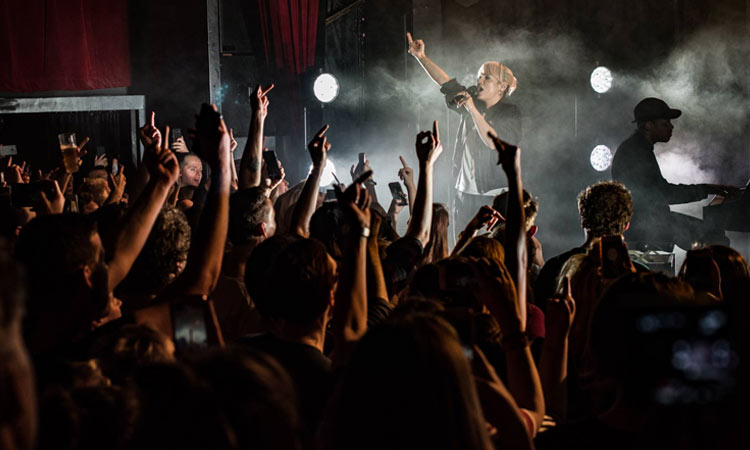 A group of people watching a band on stage, with their hands up