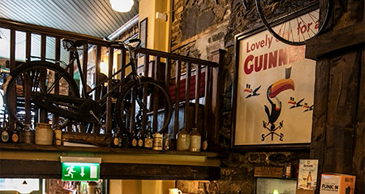 The Old Storehouse in Dublin which has a decoration of a Guinness poster and a bike sat on a mezzanine level of the bar