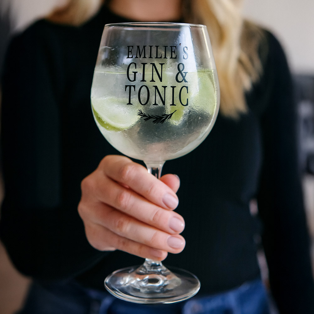 A woman holding a custom gin glass that has been personalised with the custom text Emilie's Gin & Tonic
