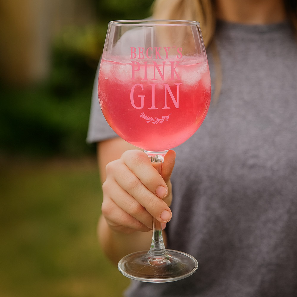 A woman holding a custom gin glass that has been personalised with the custom text Becky's Pink Gin