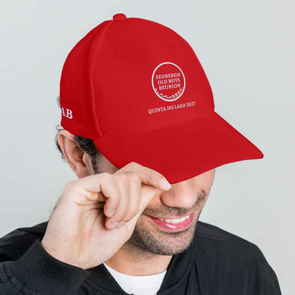 A side view of a male model wearing a red custom golf cap with a golf ball design that reads Sedbergh Old Boys Reunion inside the golf ball with Quinta Do Lago 2027 underneath it and the initials AB embroidered on the side