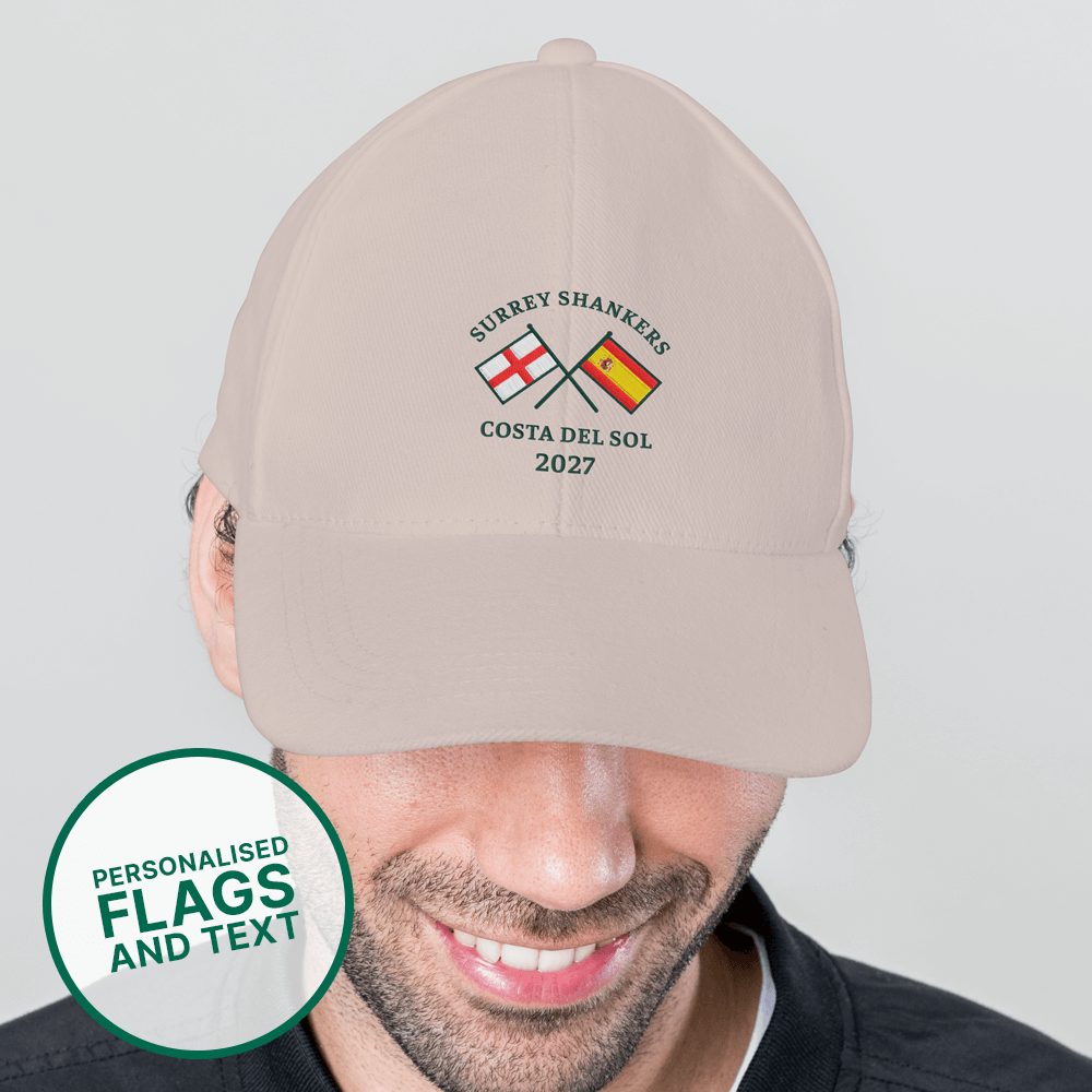 A male model wearing a custom golf cap with a multi flags design that is an England flag crossed over a Spain flag with the custom text Surrey Shankers, Costa Del Sol, 2027 