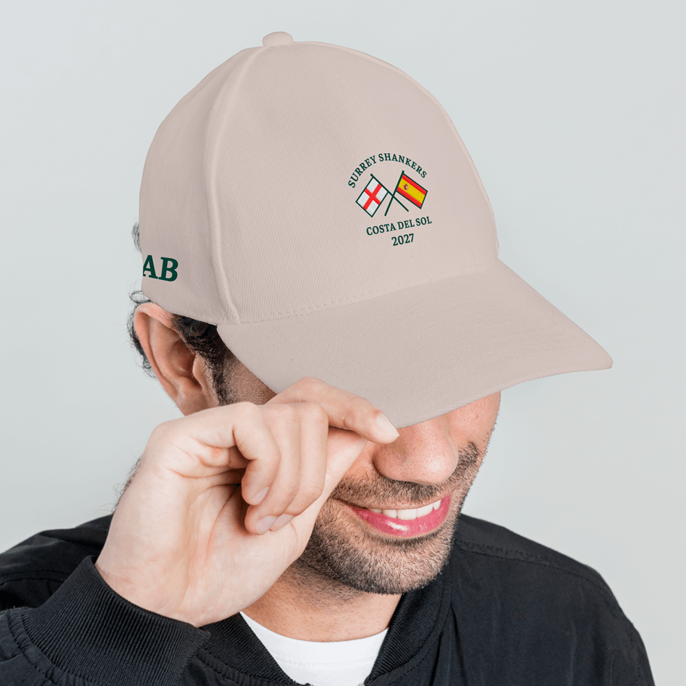 A side view of a male model wearing a custom golf cap with a multi flags design that is an England flag crossed over a Spain flag with the custom text Surrey Shankers, Costa Del Sol, 2027