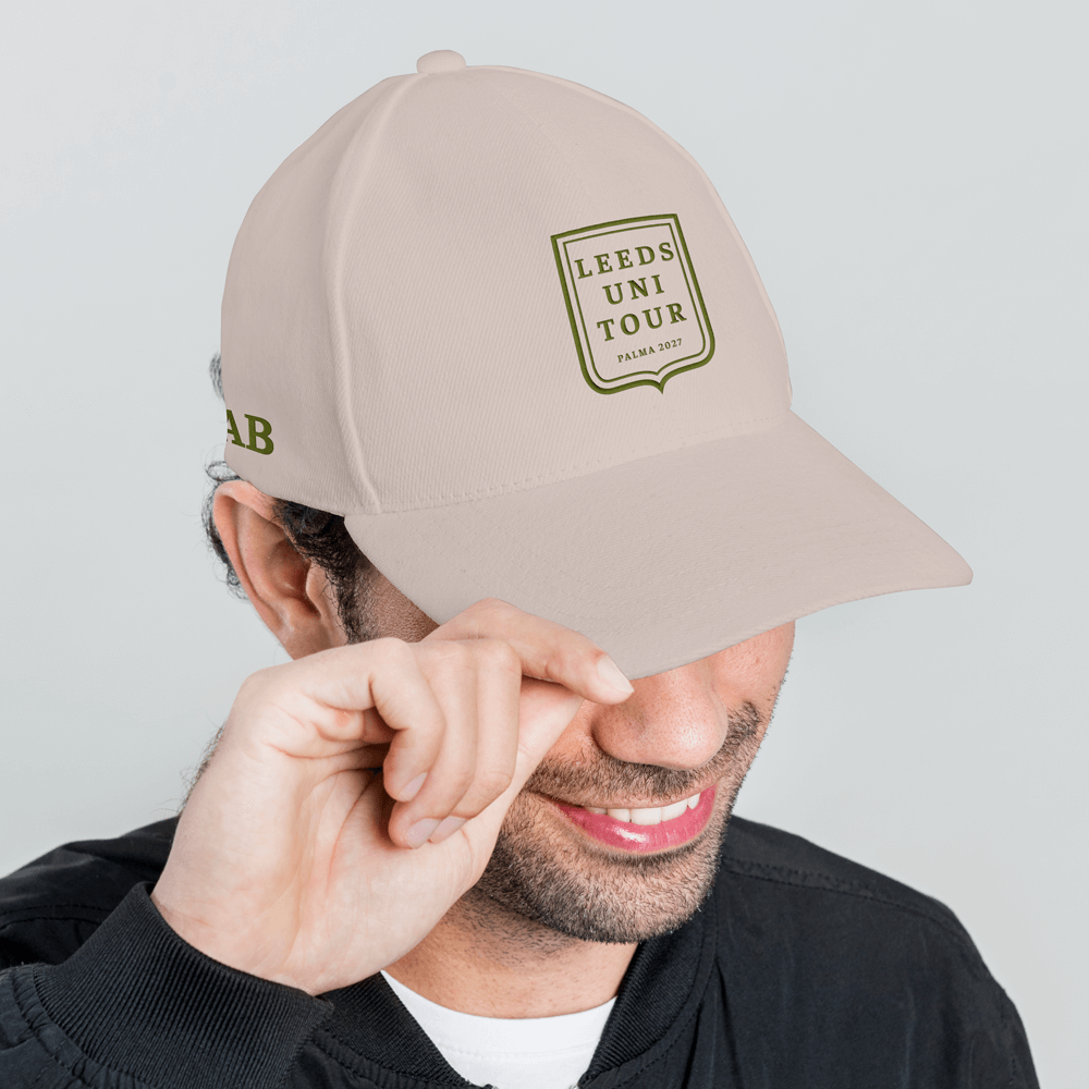 A side view of a male model wearing a beige custom golf polo shirt with a society crest design that has been personalised with Leeds Uni Tour, Palma 2027 with the initials AB embroidered onto the side