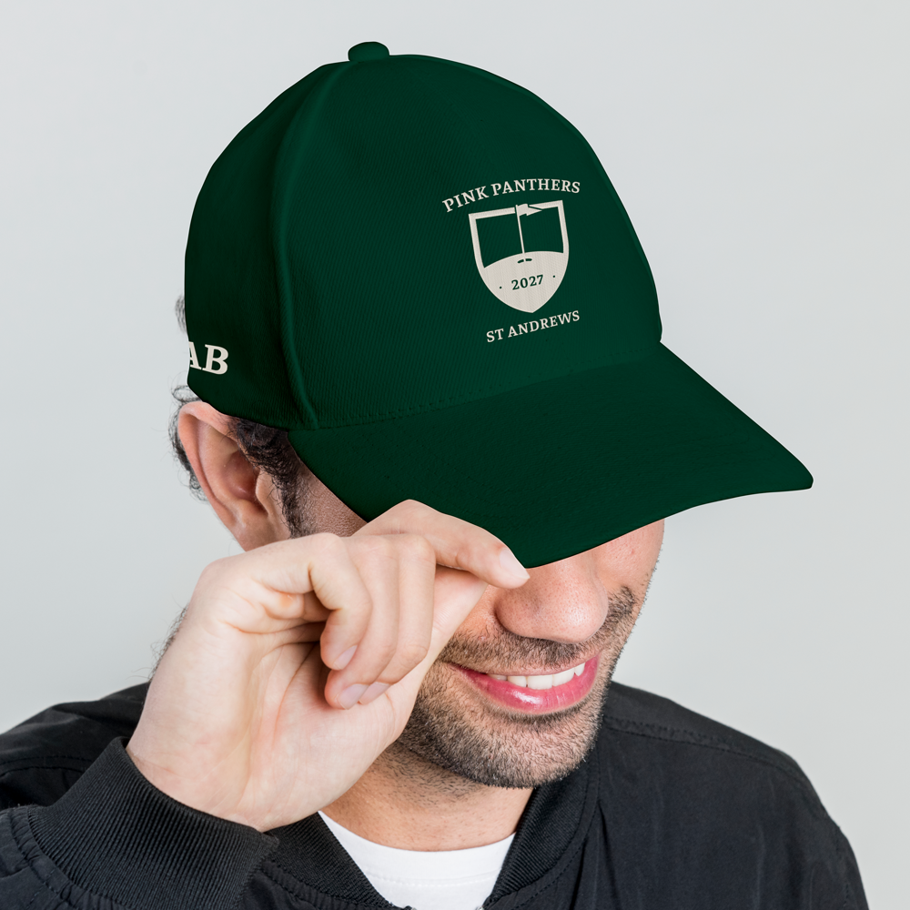 A male model wearing a green custom golf cap with a tour crest design that has been personalised with Pink Panthers, 2027, St Andrews with the initials AB embroidered on the side