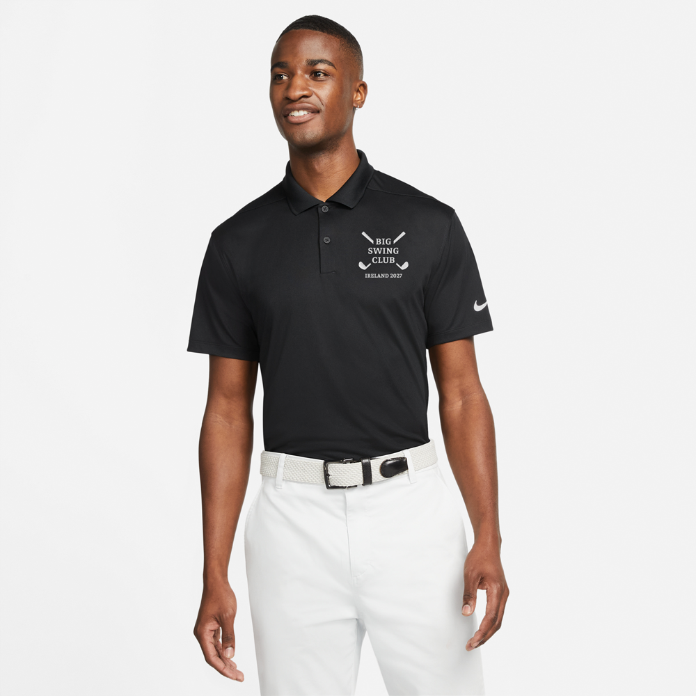 A male model wearing a black golfing shirt with an embroidered logo reading Big Swing Club with a design of two golf clubs crossed over each other in an X shape behind the words