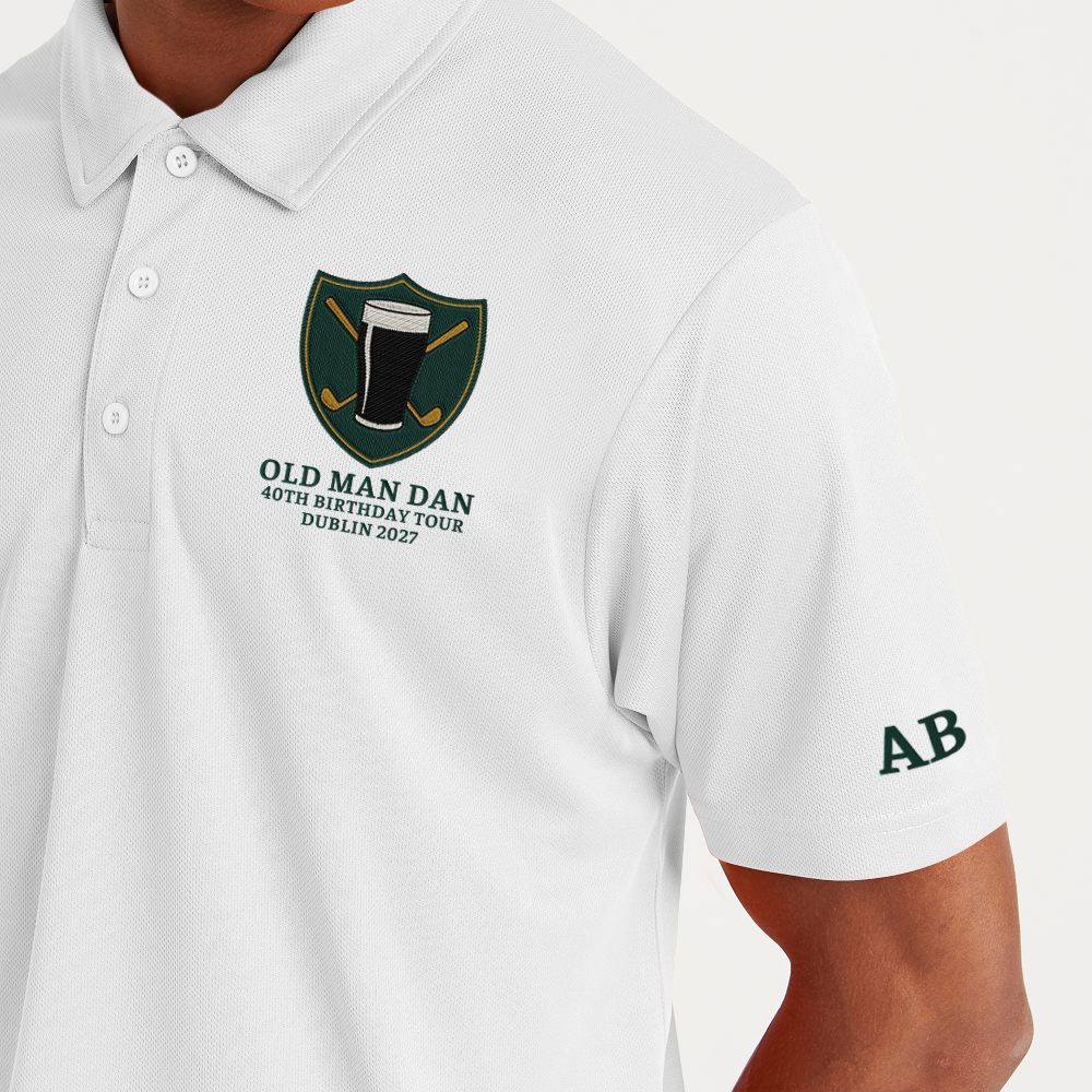 A white golfing shirt with an embroidered crest that has a pint of beer in front of golf clubs that cross over each other in an X shape with custom text reading Old Man Dan, 40th Birthday Tour, Dublin 2027