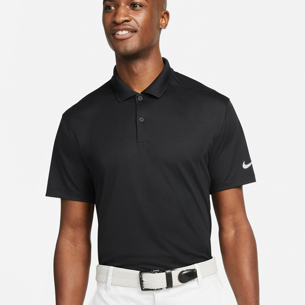 A male model wearing a black Nike Victory solid polo with the Nike swoosh on the sleeve 