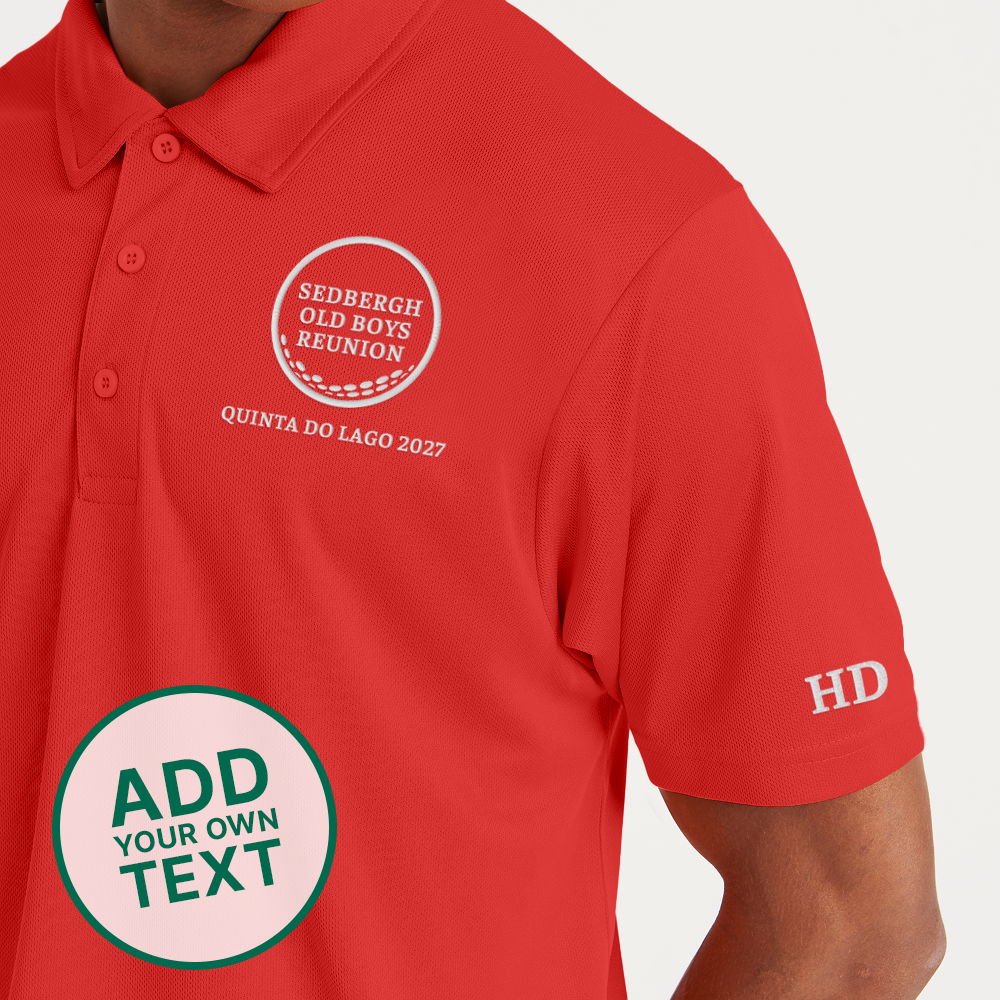 A male model wearing a red custom golf polo with a golf ball design that reads Sedbergh Old Boys Reunion inside the golf ball with Quinta Do Lago 2027 underneath it