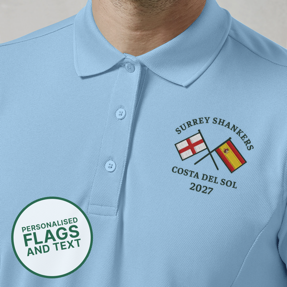 A blue custom golf polo with a multi flags design that is an England flag crossed over a Spain flag with the text Surrey Shankers, Costa Del Sol, 2027 