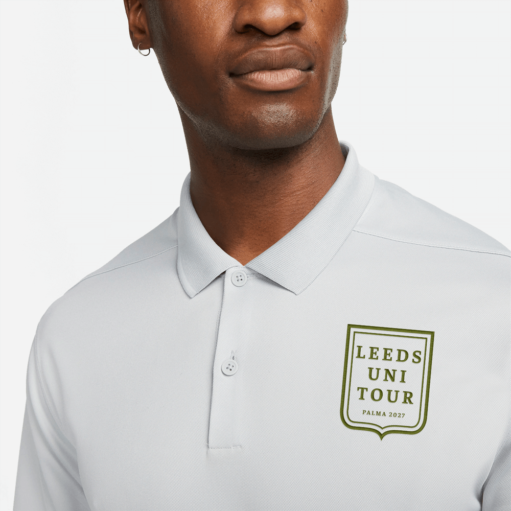 A male model wearing a white custom golf polo shirt with a society crest design that has been personalised with Leeds Uni Tour, Palma 2027