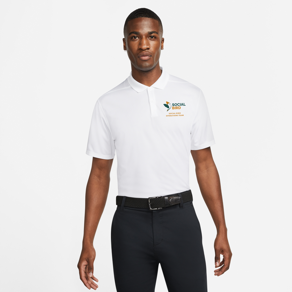 A male model wearing a white golfing shirt with a golf logo embroidered onto it