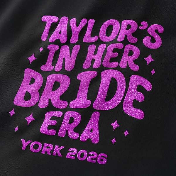 A black hen do shirt with custom 'puff print' bubble writing that reads Taylor's in her Bride Era, York, 2026