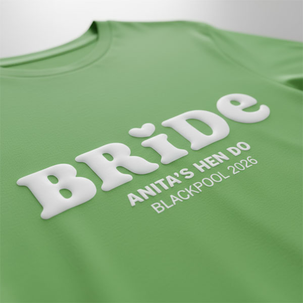 A green hen do shirt with custom white 'puff print' bubble writing that reads Bride (with a heart above the I) as well as Anita's Hen Do, Blackpool 2026
