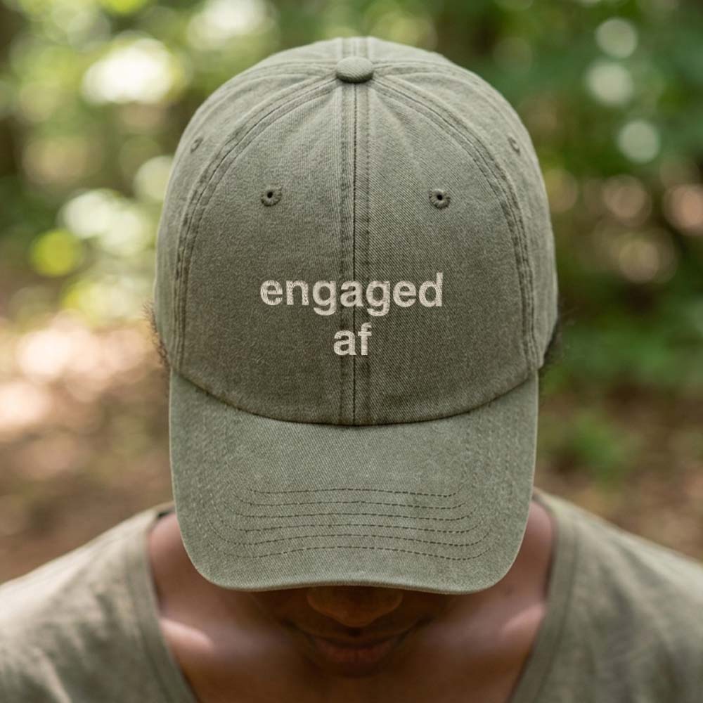 A female model wearing a premium hen do cap in green that has been embroidered with the phrase engaged af in a tusk font with a background of a blurred out forest