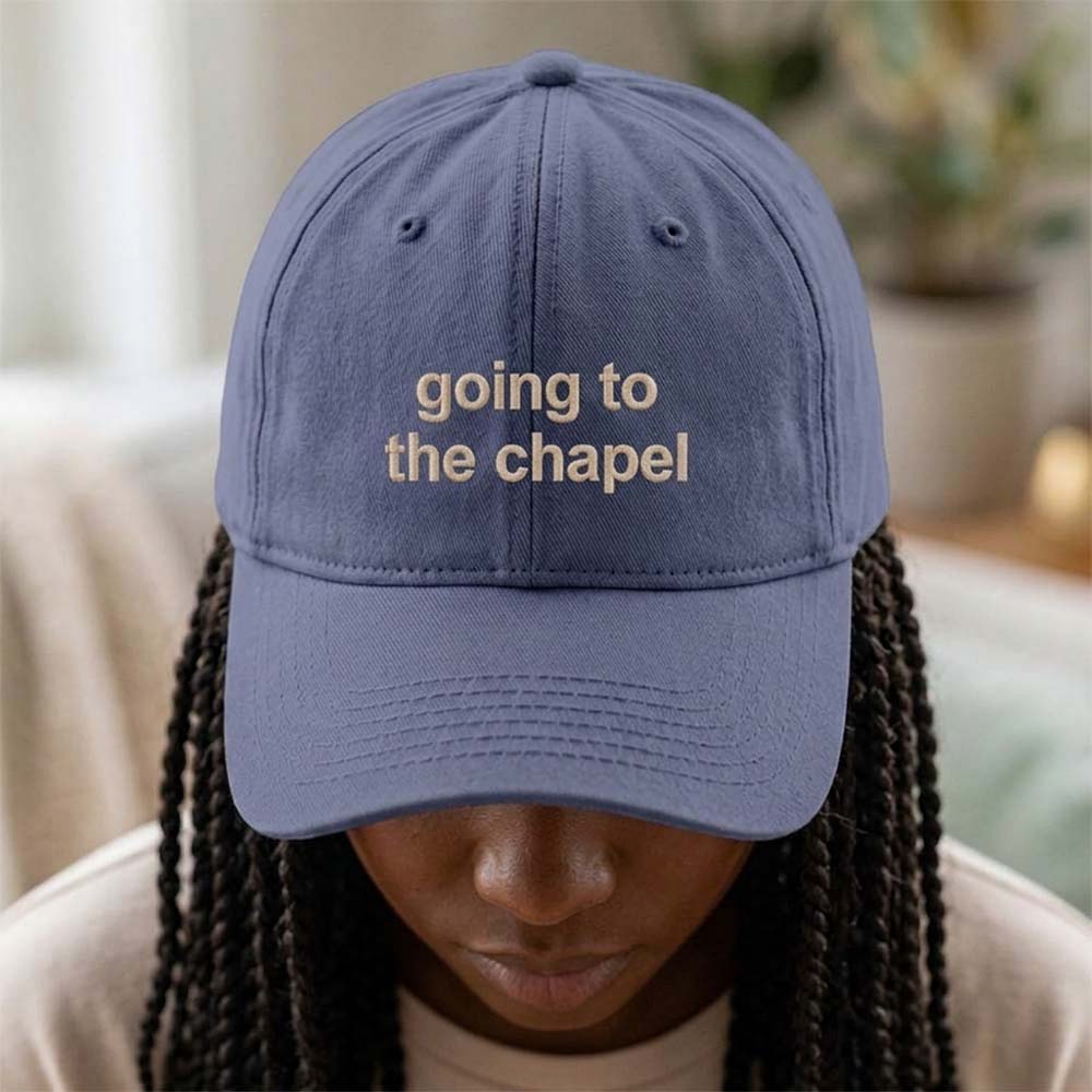 A female model wearing a premium hen do cap in blue with the text going to the chapel embroidered on it in a tusk font